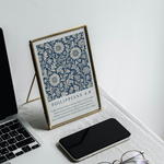 Laptop, phone, eyeglasses, and framed text on a white surface