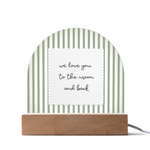 A wooden arch-shaped acrylic plaque with green and white vertical stripes and a white sign reading 'we love you to the moon and back'