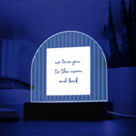 A wooden arch-shaped acrylic plaque with green and white vertical stripes and a white sign reading 'we love you to the moon and back'