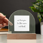 A wooden arch-shaped acrylic plaque with green and white vertical stripes and a white sign reading 'we love you to the moon and back'