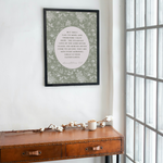 Framed artwork on a wall above a wooden desk with a large window in the background.